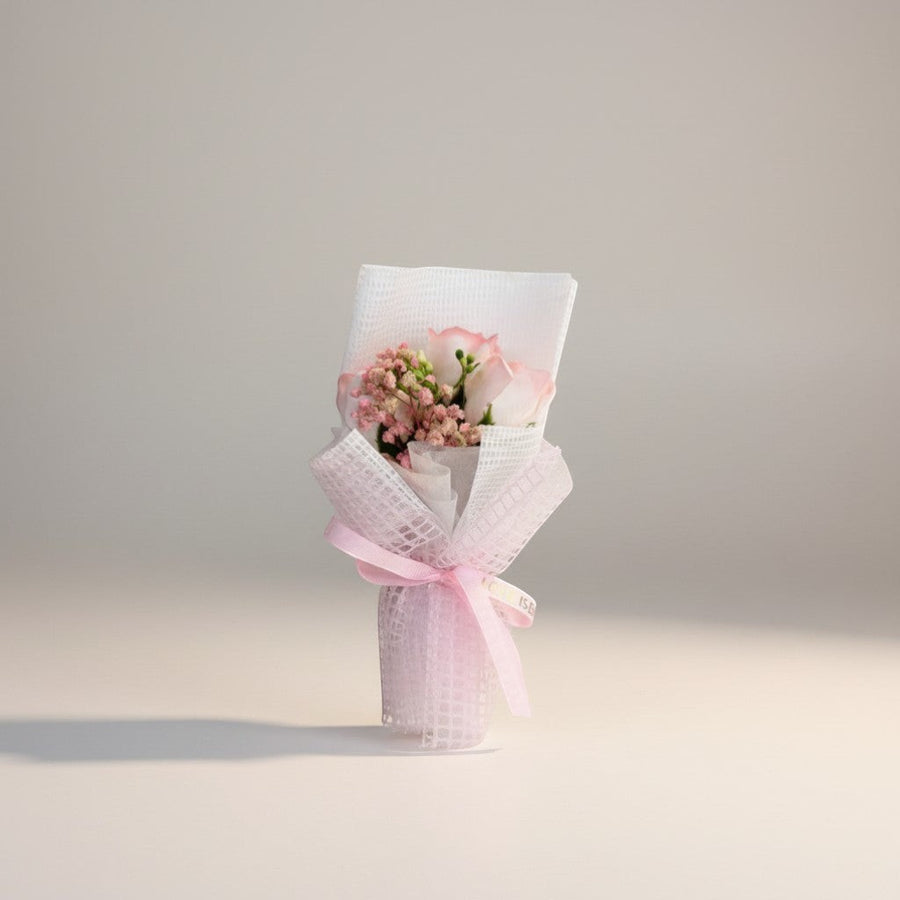 eRamis pink roses and baby's breath bouquet with white mesh wrap and pink ribbon.