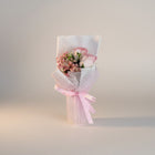 eRamis pink rose and baby's breath bouquet with white mesh wrap and pink ribbon.