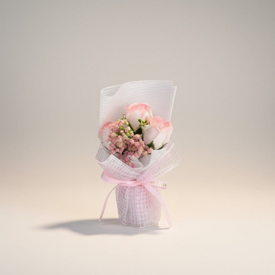 eRamis pink and white roses bouquet with baby's breath, wrapped in white mesh and tied with a pink ribbon.