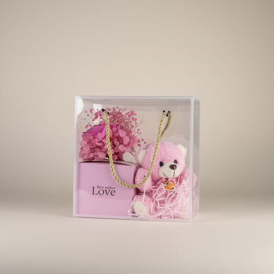 eRamis pink teddy bear gift set with preserved flowers and 'Best wishes Love' card in a clear gift bag.
