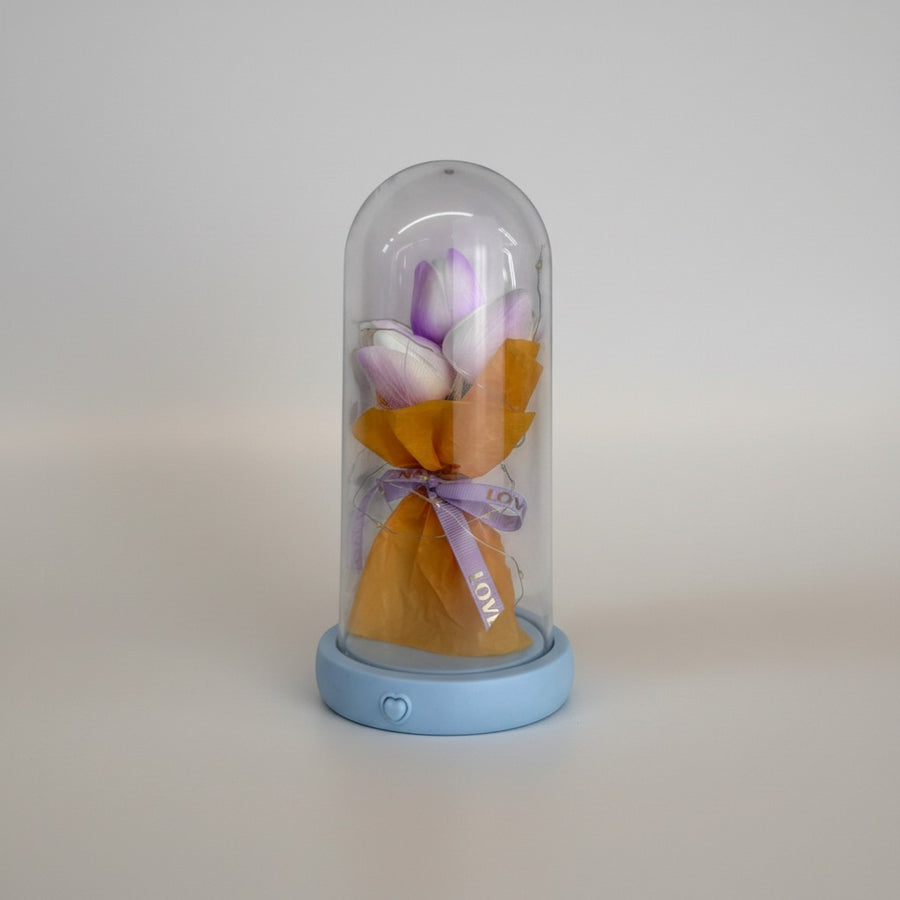 eRamis preserved purple and white tulips under a glass dome with fairy lights and a blue base.