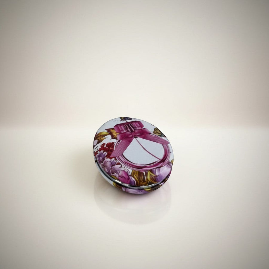 eRamis round compact mirror with floral print and pink ribbon detail. Features a decorative perfume bottle design.