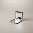 eRamis square compact mirror with a polished silver-tone metal frame and clear reflective surfaces.