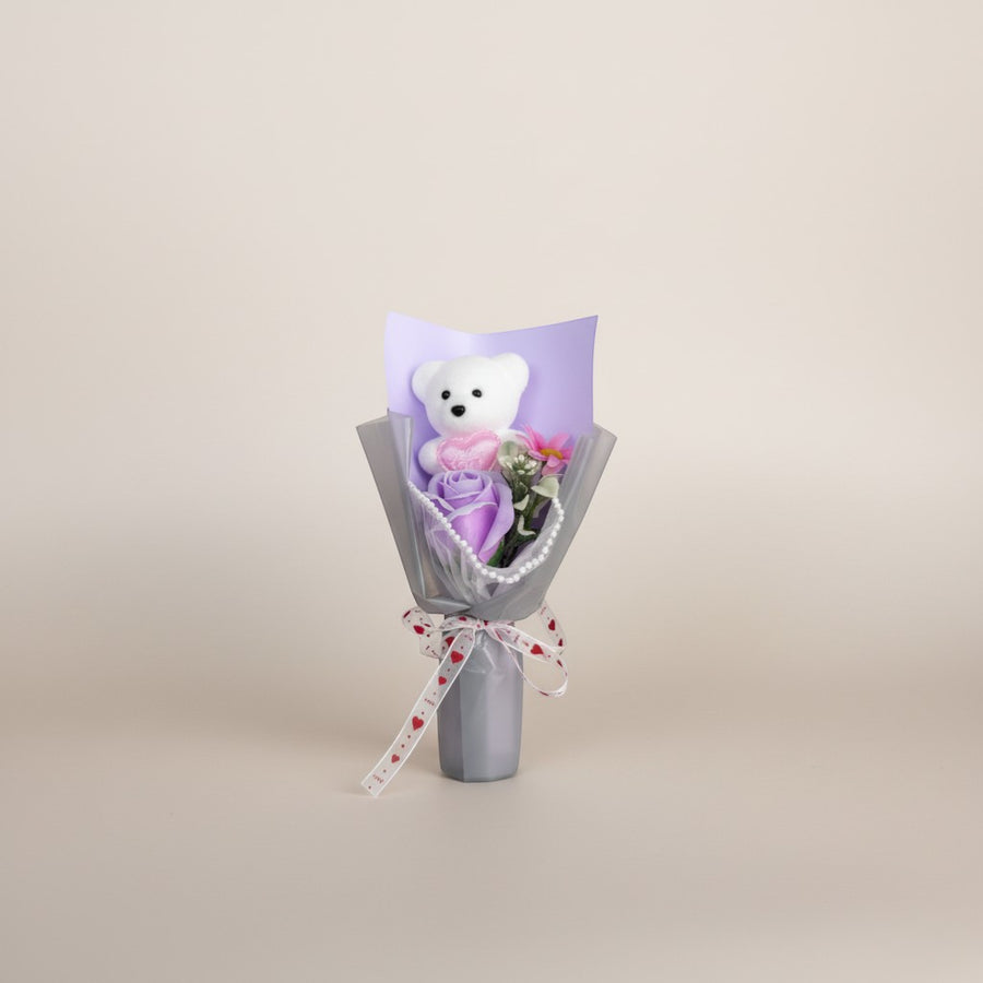 eRamis white plush teddy bear with pink heart, purple rose, and pink flowers in bouquet with pearl trim and heart ribbon.