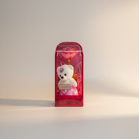 eRamis white plush teddy bear with pink skirt and heart gem, holding 'I Love You' sign, next to a pink galaxy rose in gift box.