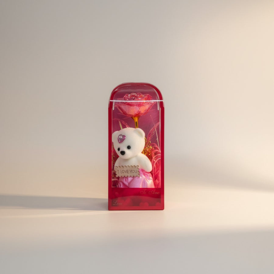 eRamis white plush teddy bear with pink skirt and heart gem, holding 'I Love You' sign, next to a pink galaxy rose in gift box.