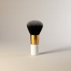 eRamis thick makeup brush with dense grey and black synthetic bristles and a white handle with a gold band.