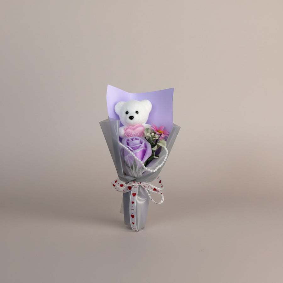 eRamis white teddy bear bouquet with purple rose, pink flower, and pearl accents, tied with a love heart ribbon.