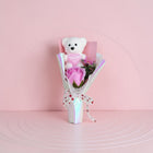 eRamis white teddy bear with pink "I Love You" heart, holding a pink rose bouquet with decorative ribbon and pearls.