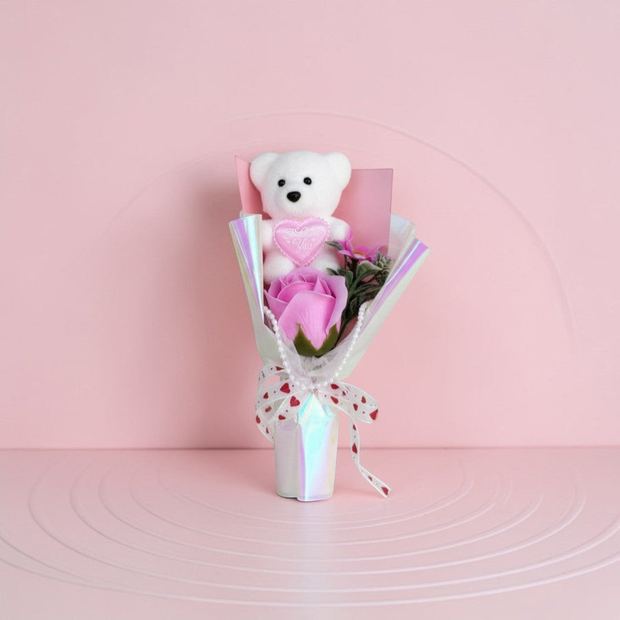 eRamis white teddy bear with pink "I Love You" heart, holding a pink rose bouquet with decorative ribbon and pearls.