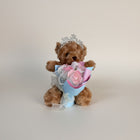 eRamisHere brown teddy bear wearing a tiara, holding a bouquet of pink and white roses with pearl accents.
