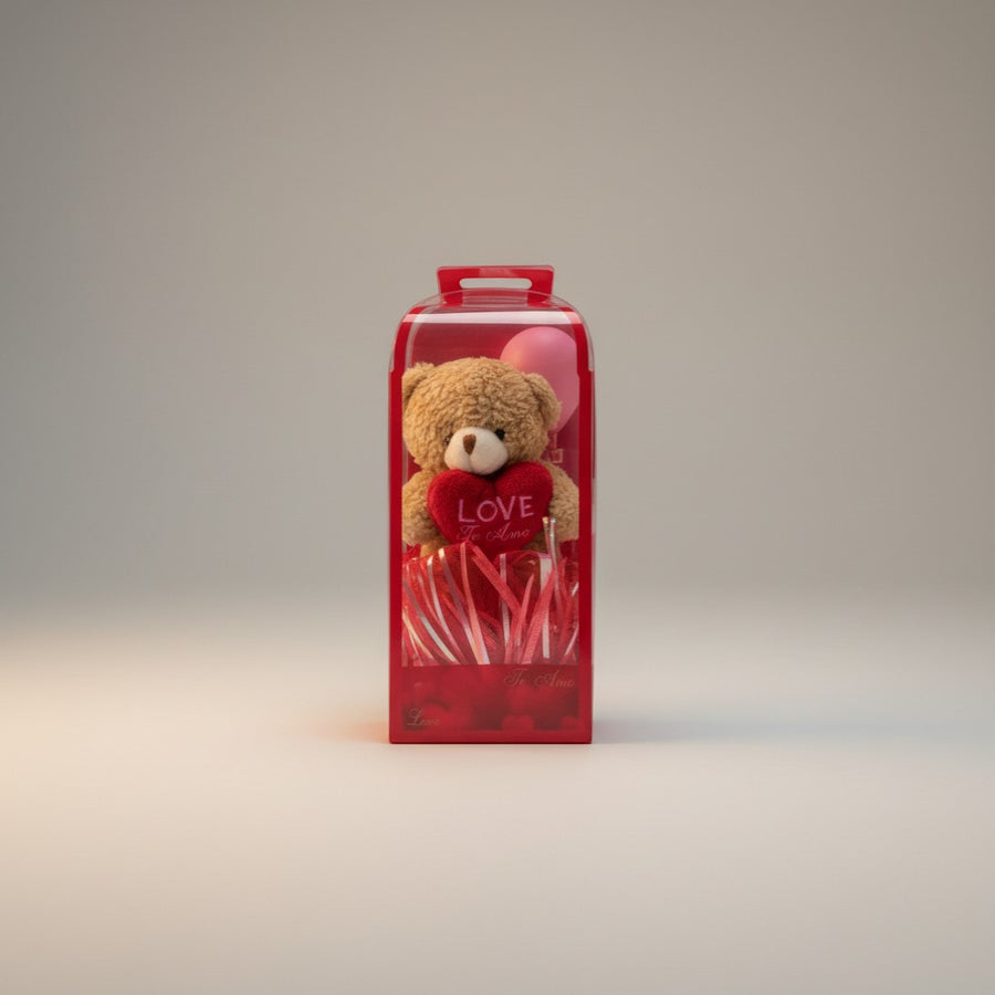 eRamisHere teddy bear holding a red heart with 'LOVE' text, in a gift box with red streamers.