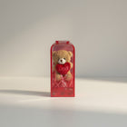 eRamisHere small brown teddy bear holding a red heart with 'LOVE' inscribed, in a clear gift box with red ribbon.