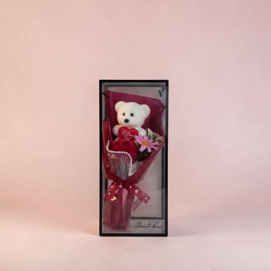 eRamisHere white teddy bear holding a red heart with 'I Love You' text, surrounded by red roses and pink flowers in a clear box.