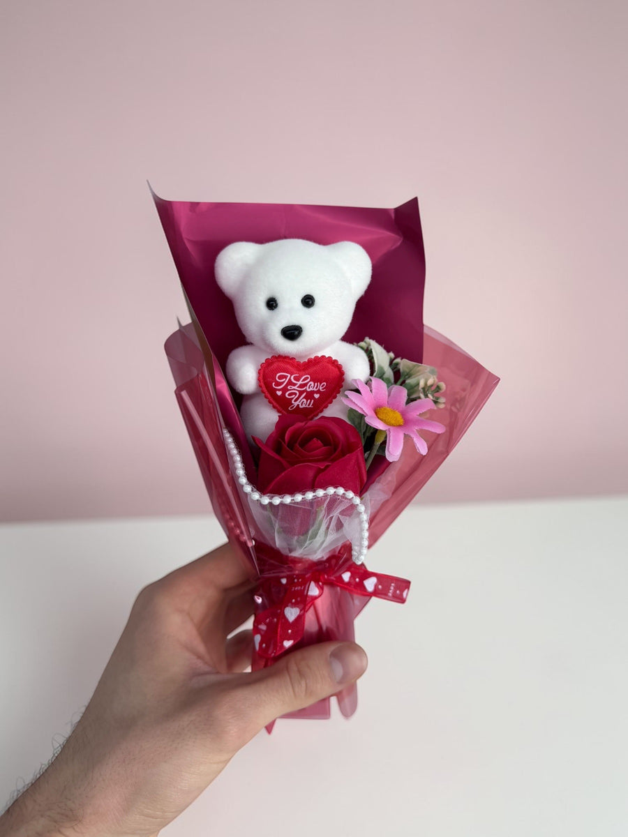 eRamisHere white teddy bear holding a red heart with 'I Love You' text, with a red rose and pink flowers. Gift bouquet.