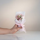 eRamis pink roses and baby's breath bouquet, wrapped in white mesh with a pink ribbon that says "LOVE IS E".