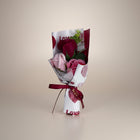 eRamis bouquet of artificial red and pink roses, wrapped in white paper with red hearts and 'Love' text, tied with a red ribbon.